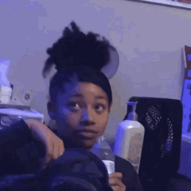 a woman is making a funny face while holding a bottle of water in her hand .
