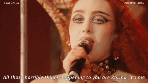 a woman singing into a microphone with the words " all those horrible things happening to you are karma "
