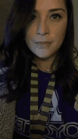 a woman wearing a purple shirt and a striped scarf .