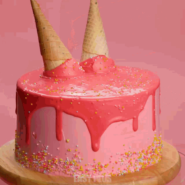 a cake with pink frosting and sprinkles on a wooden cutting board