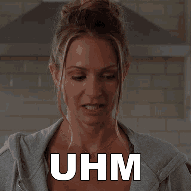 a woman in a grey sweatshirt says uhm in white letters
