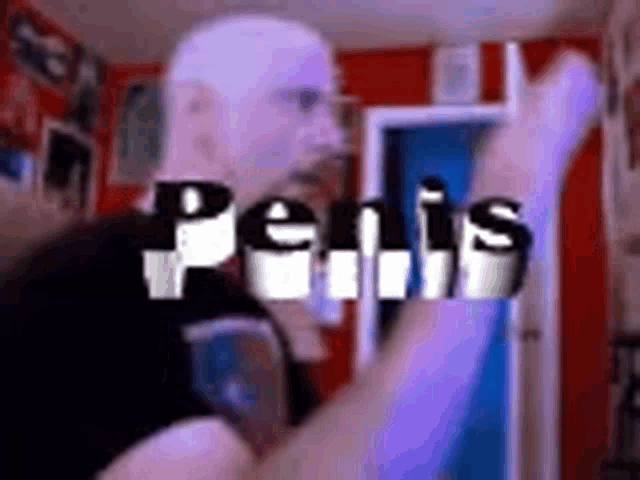 a man in a white mask is standing in a room with the word penis in the background .