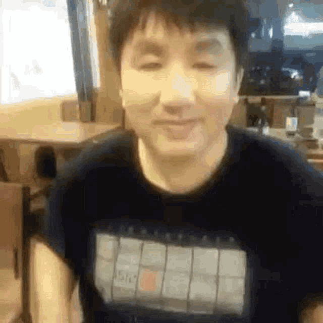 a man wearing a black t-shirt is sitting in a restaurant .