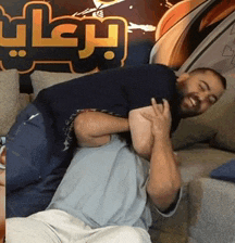 two men are wrestling on a couch in front of a sign that says ' arabia '