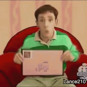 a man in a green shirt is sitting in a red chair holding a piece of paper .