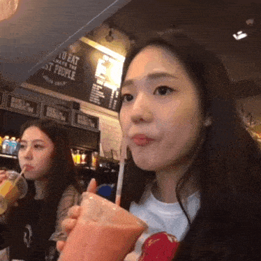 a girl drinking a smoothie with a straw in front of a sign that says to eat always be the best people