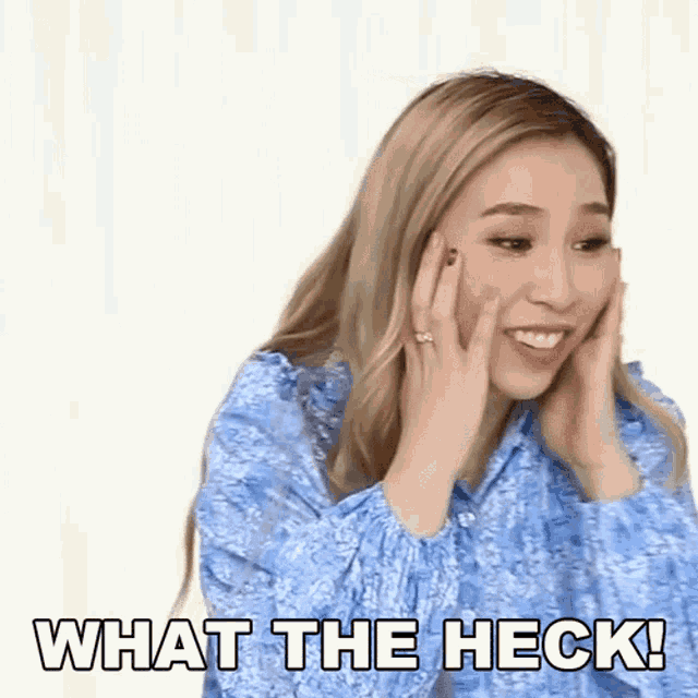 a woman in a blue shirt with her hands on her face and the words what the heck !
