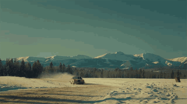 a car is driving down a snowy road with mountains in the background and the words bring wynnan home