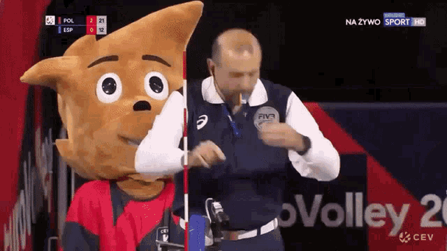 a man with a mascot on his head stands next to a volleyball referee