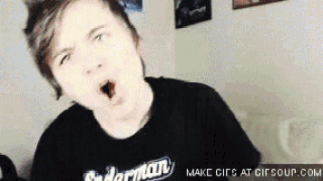 a young man wearing a spiderman shirt is yawning .
