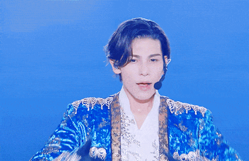 a man in a blue and gold jacket with a microphone on his head