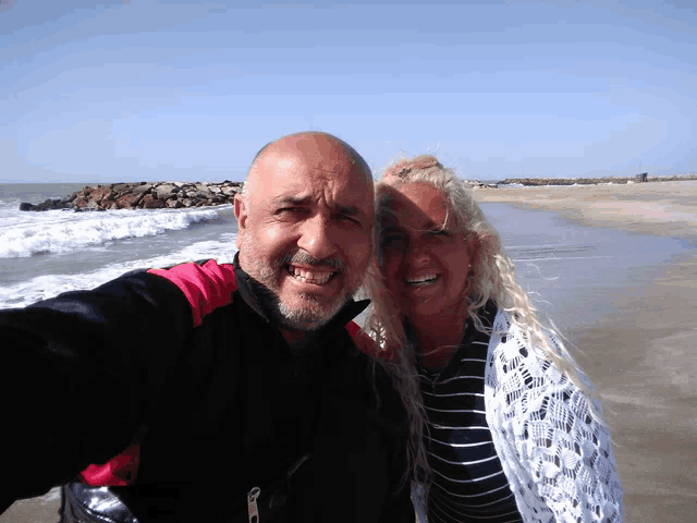a man and a woman are posing for a picture on a beach