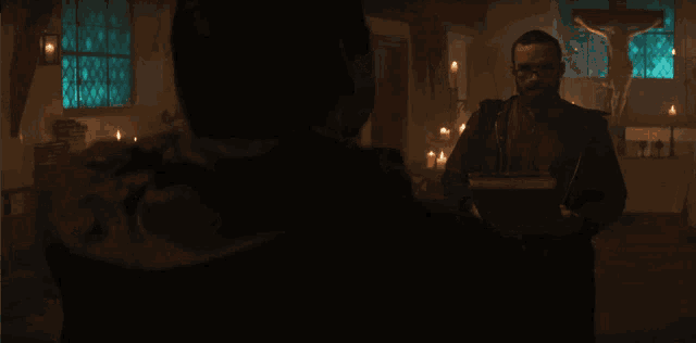 a man with glasses and a beard is standing in a dark room with candles