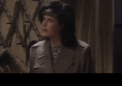 a woman in a trench coat is speaking in a foreign language with a caption that says słuchajcie uważnie