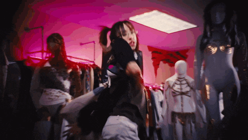 a woman is standing in front of a row of mannequins