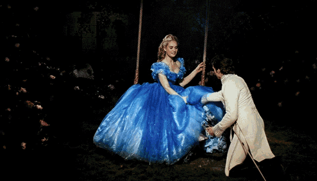 a woman in a blue dress is being helped by a man in a white suit