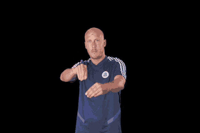 a bald man wearing a blue adidas shirt is pointing