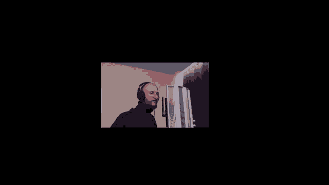 a man wearing headphones stands in front of a computer monitor