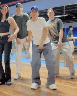 a group of people are standing next to each other on a wooden floor and dancing .