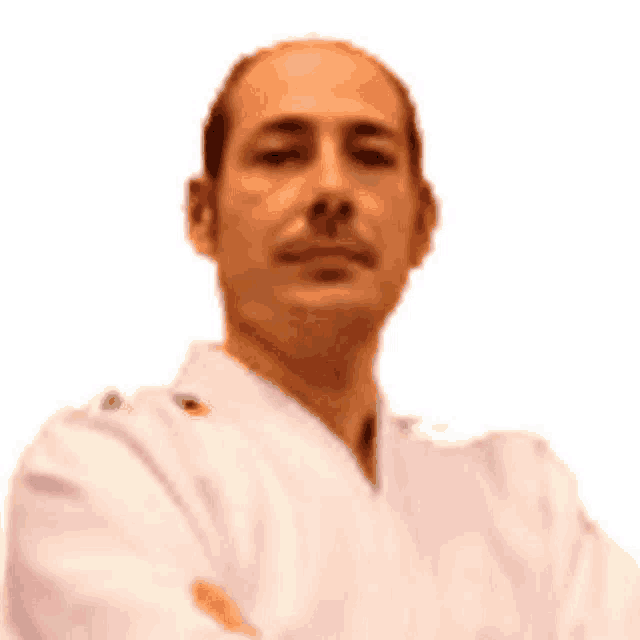 a man with his arms crossed is wearing a white karate uniform