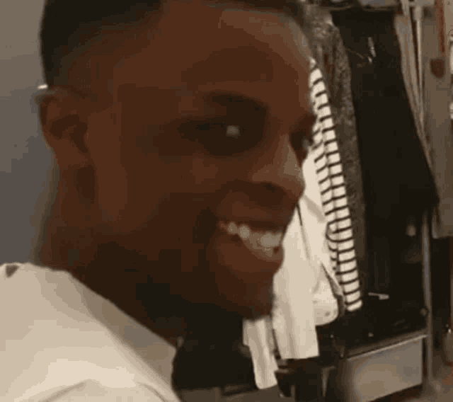a man in a white shirt is smiling in front of a closet