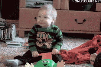 a baby wearing a green and black striped shirt with a truck on it is playing with a green toy