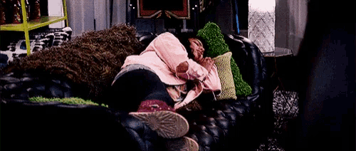 a woman in a pink jacket is sleeping on a couch