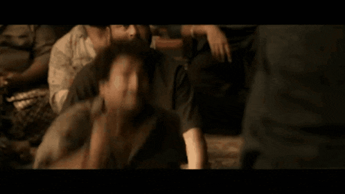 a group of men are sitting on the floor in a dark room .