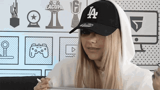 a woman wearing a la dodgers hat and hoodie