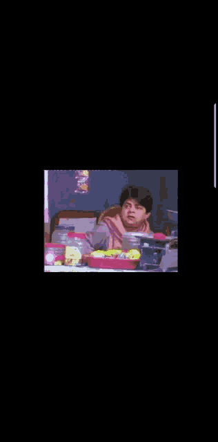 a woman in a pink scarf is sitting at a table with a tray of lemons on it .