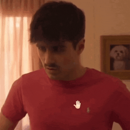 a man with a mustache is wearing a red shirt with a hand on the chest .