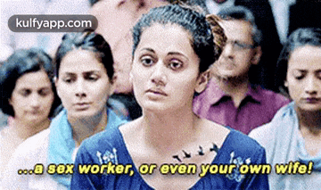 a woman in a blue shirt is sitting in front of a crowd of people .