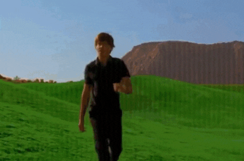 a man in a black shirt is running in a green field .