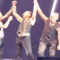 a group of men are standing on a stage with their hands in the air