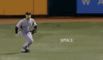 a baseball player is laying on his back on the field with the word joke behind him .
