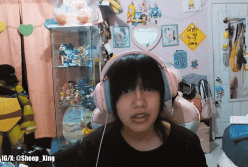 a girl wearing pink headphones is sitting in front of a sign that says sheep king