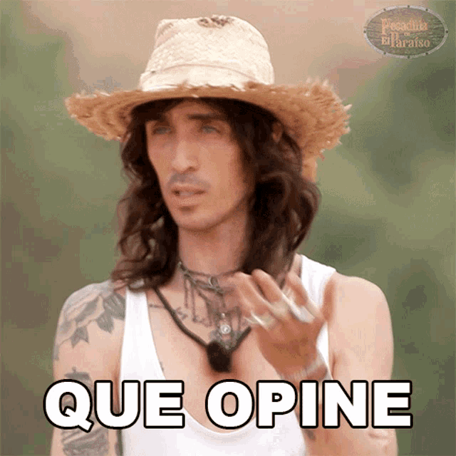 a man with long hair wearing a straw hat and a white tank top says que opine