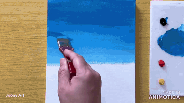 a painting of a beach is being painted on a canvas by joony art
