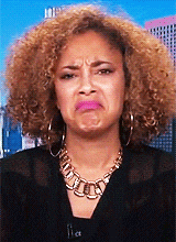 a woman with curly hair is wearing a gold necklace and earrings