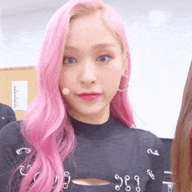a woman with pink hair is wearing a black top and earrings with the number 383 on it