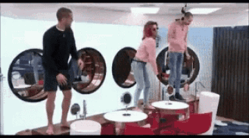 a group of people are standing around a table in a room with a lot of mirrors .