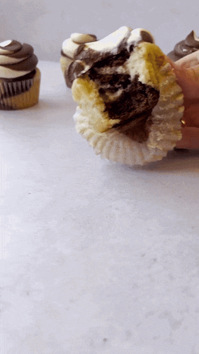 a person holding a cupcake with a bite taken out of it