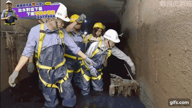 a group of people wearing hard hats and overalls are working on a construction site