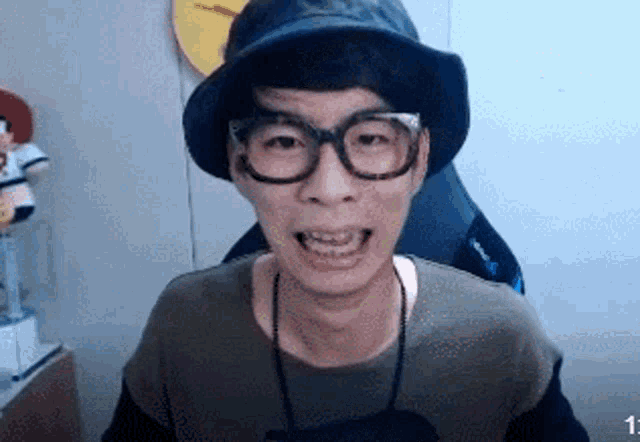 a man wearing a hat and glasses is making a face .