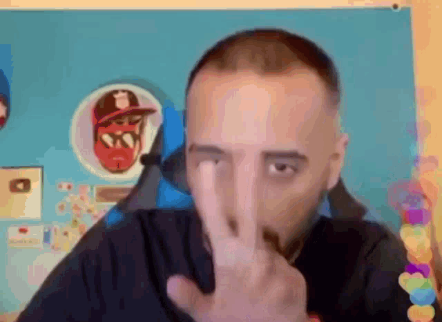 a man with a beard is making a peace sign with his hand in front of his face .