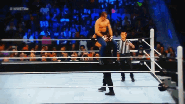 a man in a wrestling ring with a referee in front of a crowd