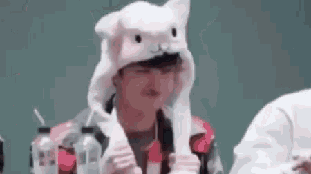 a man is wearing a white cat hat and holding a bottle .