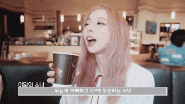 a woman with pink hair is holding a cup of coffee in a restaurant