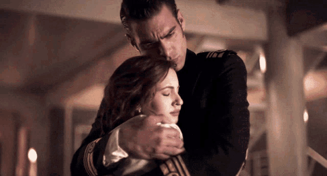 a man in a uniform is hugging a woman