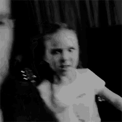 a black and white photo of a little girl in a white shirt .